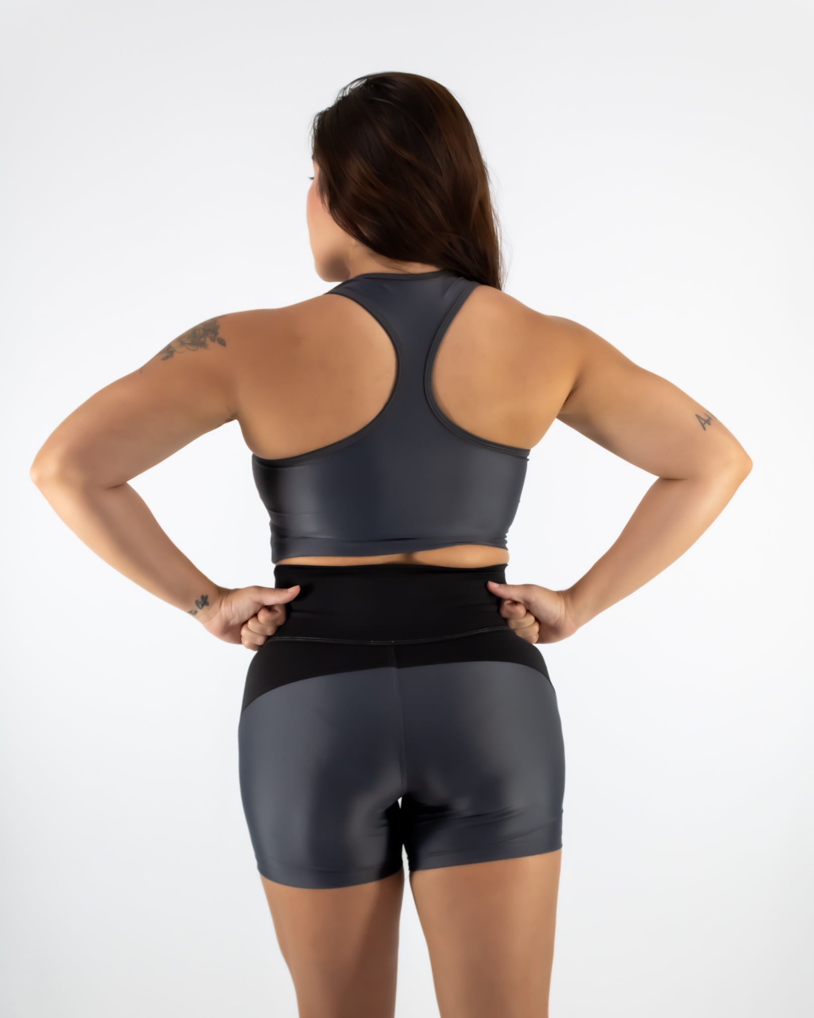 Woman wearing a black sports bra and shorts on a white background