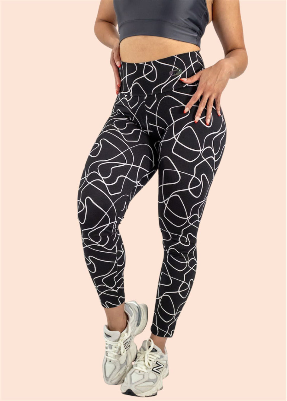 Person wearing black leggings with white abstract pattern on a beige background