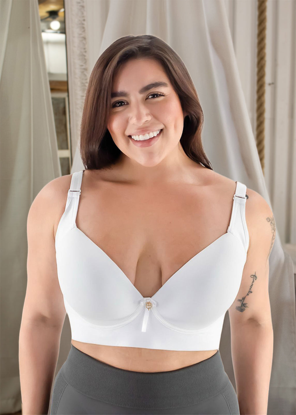 Woman wearing a white bralette with gray leggings indoors.