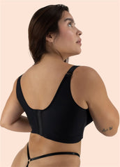 Woman wearing a black bralette on a beige background