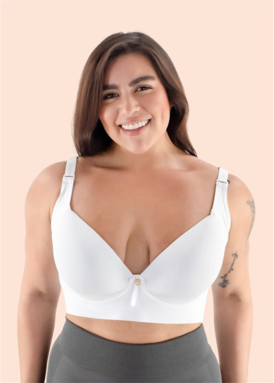 Woman wearing a white bralette with gray leggings on a beige background