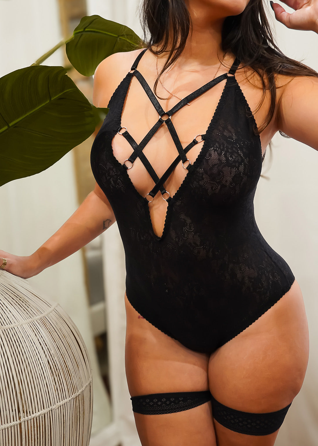 Person wearing a black lace bodysuit with strappy details.