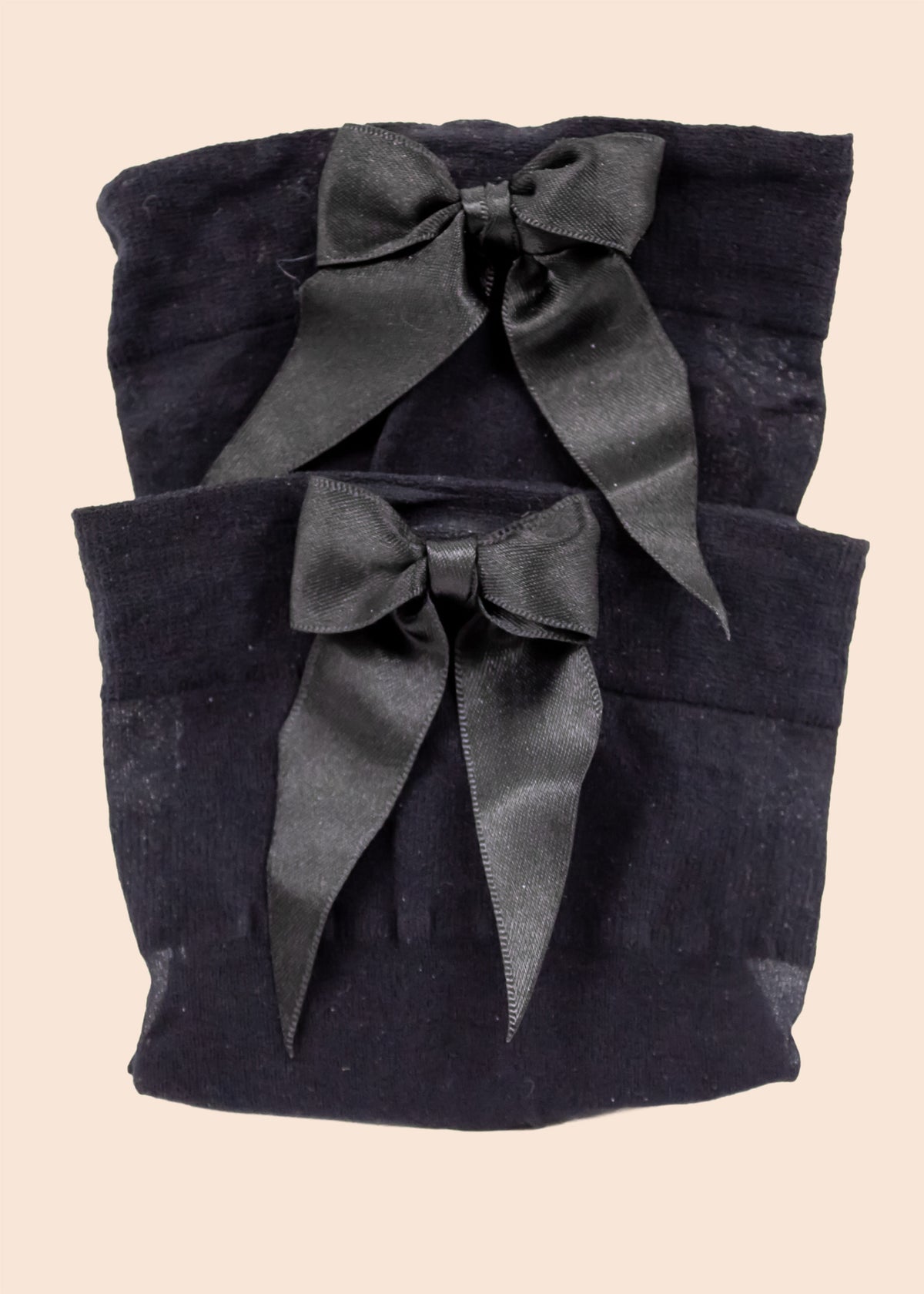Two black fabric pouches with satin ribbons on a beige background