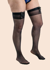 Black sheer stockings with garters worn by a person on a beige background