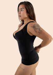 Woman wearing a black tank top against a beige background