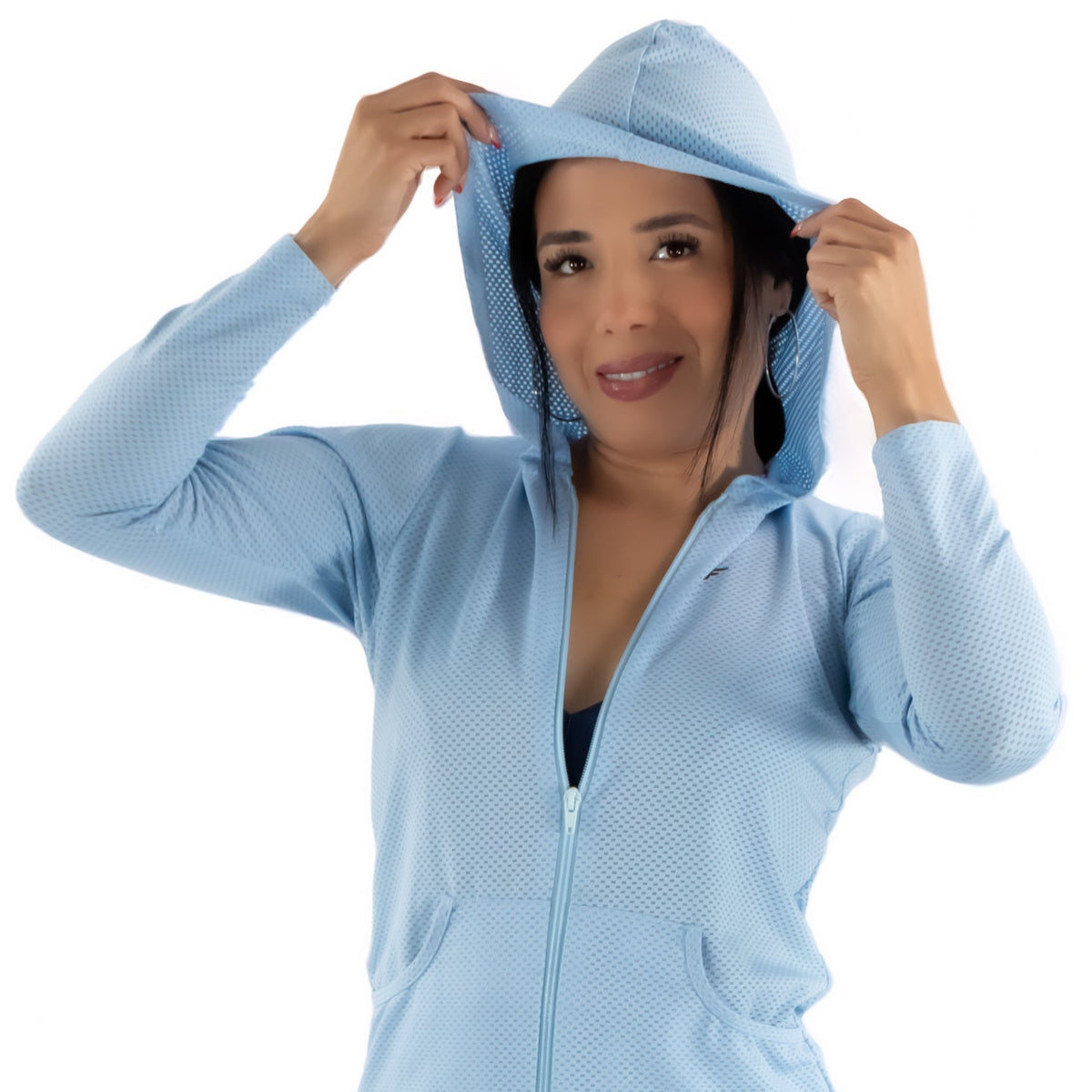 Woman wearing a light blue zip-up hoodie with a hood, standing against a white background.