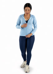 Woman wearing a light blue hoodie and dark blue leggings on a white background