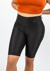 Person wearing black athletic shorts with a subtle pattern on a white background