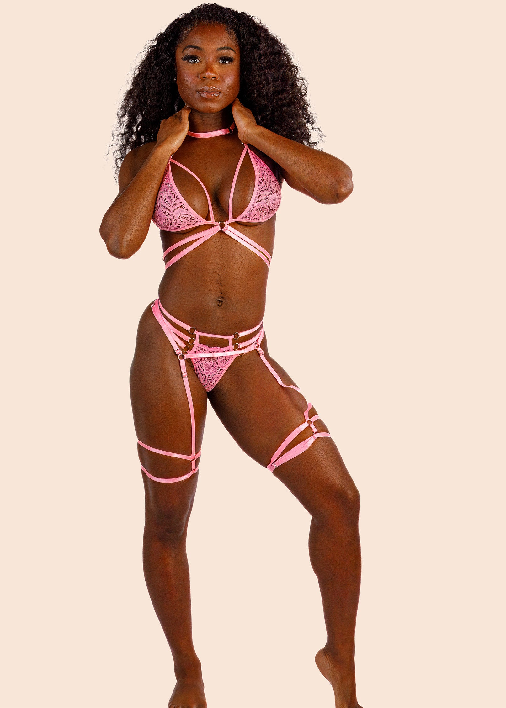 Model wearing a pink lingerie set against a beige background