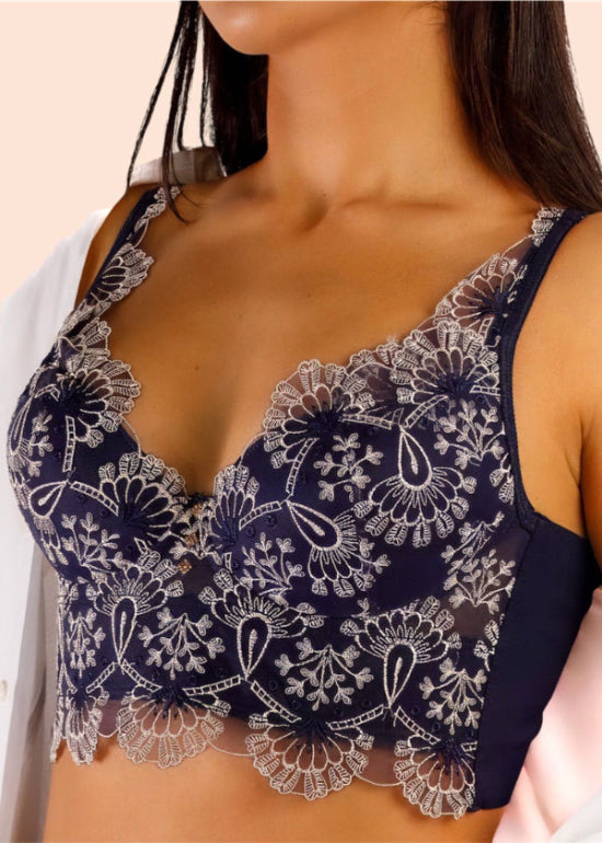 Navy blue lace bralette worn by a person on a beige background