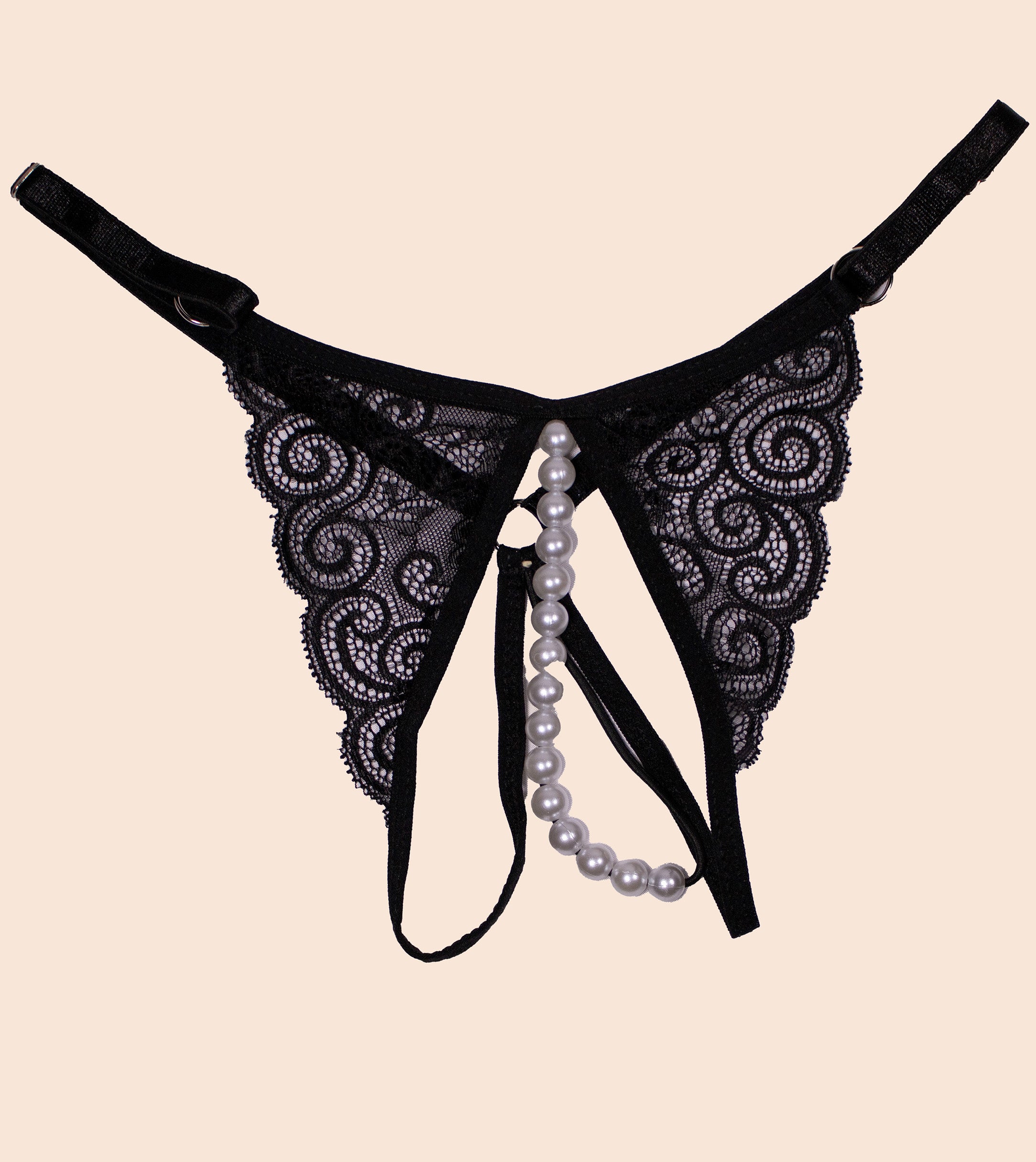 Black lace lingerie with pearl accents on a beige background