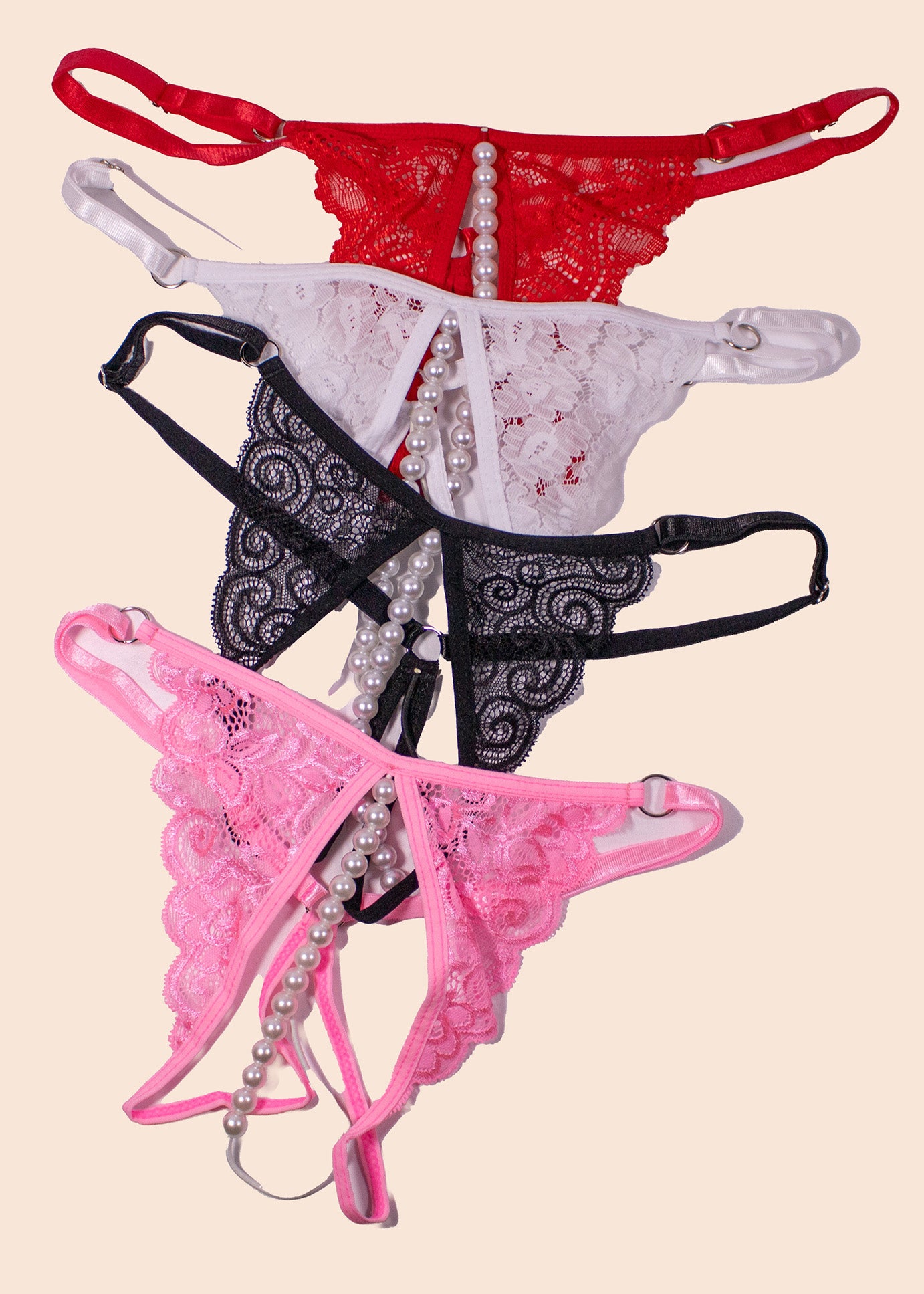 Three pairs of lingerie in red, black, and pink on a beige background