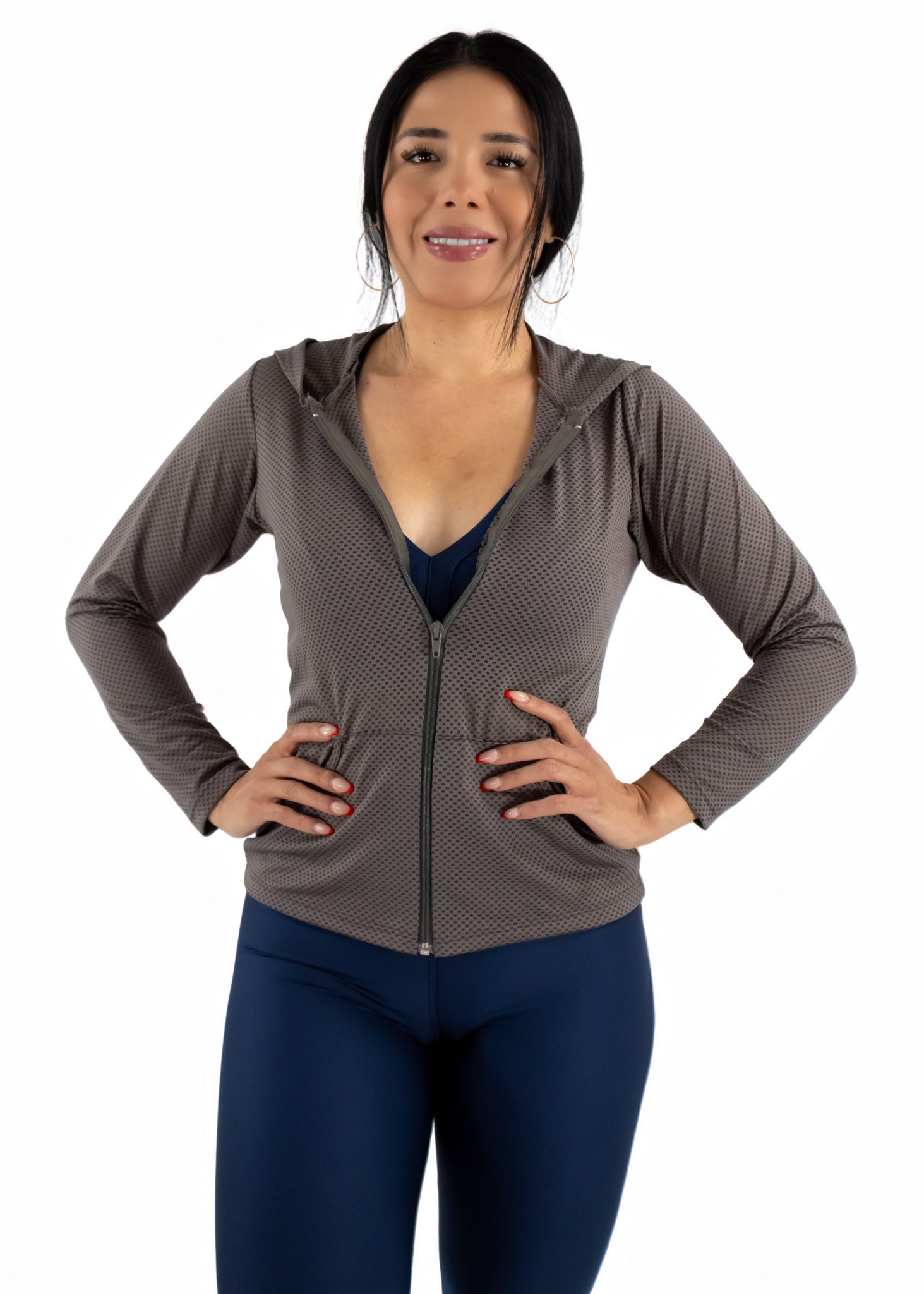 Woman wearing a brown zip-up hoodie and blue leggings on a white background