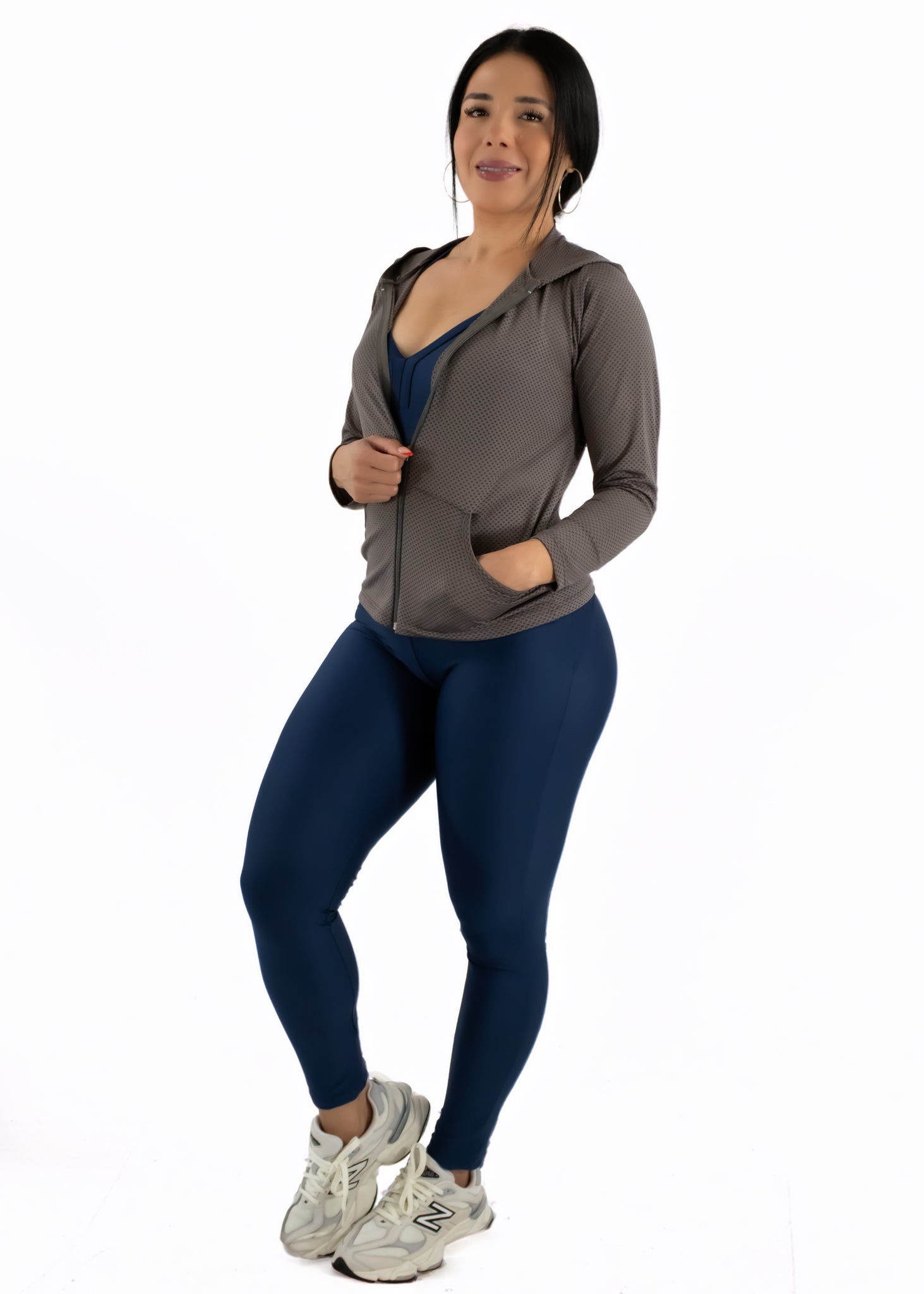 Woman wearing a gray hoodie and blue leggings on a white background