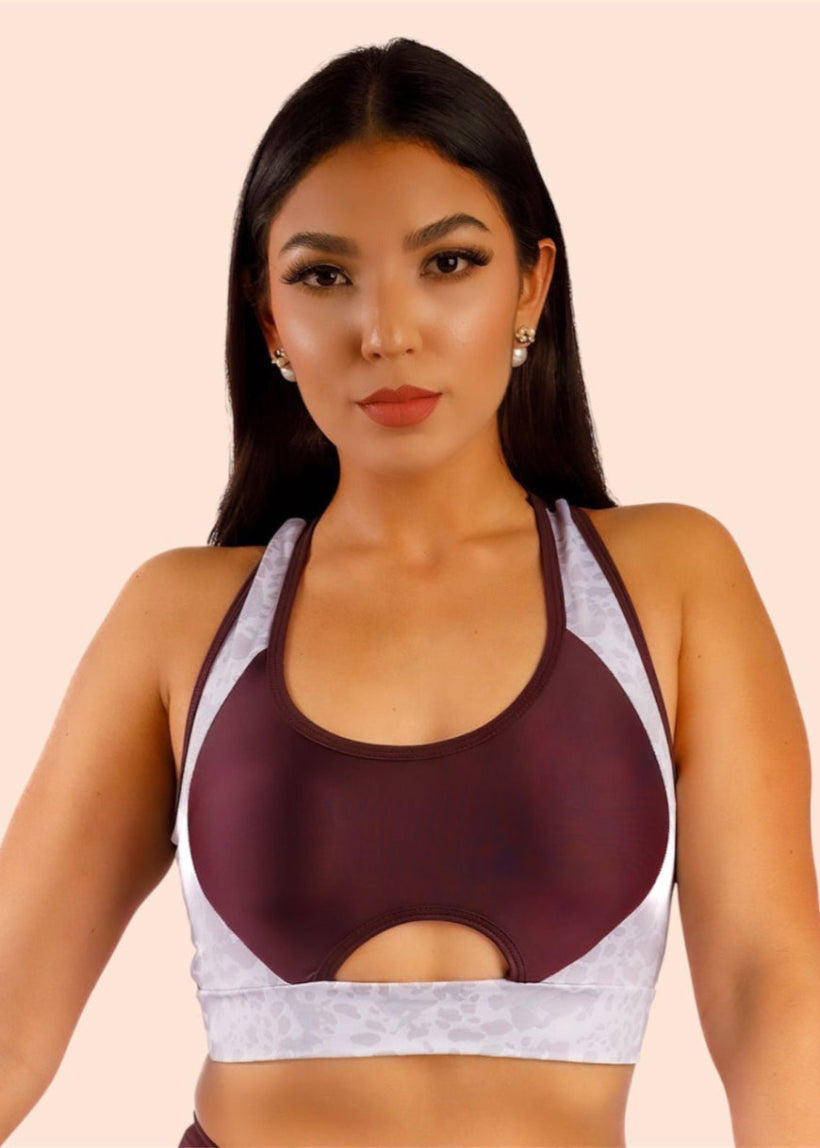 Woman wearing a maroon and white sports bra on a beige background