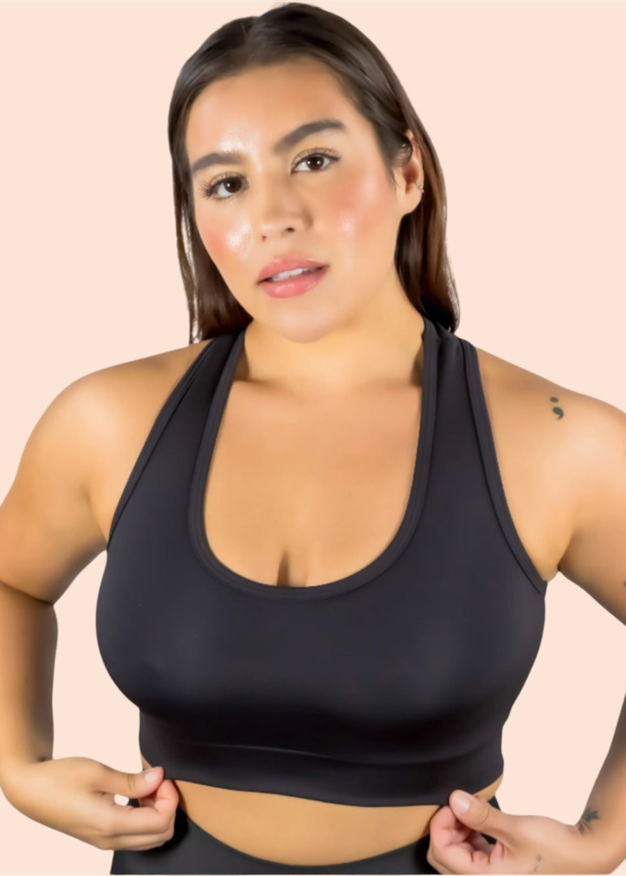 Woman wearing a black sports bra against a beige background