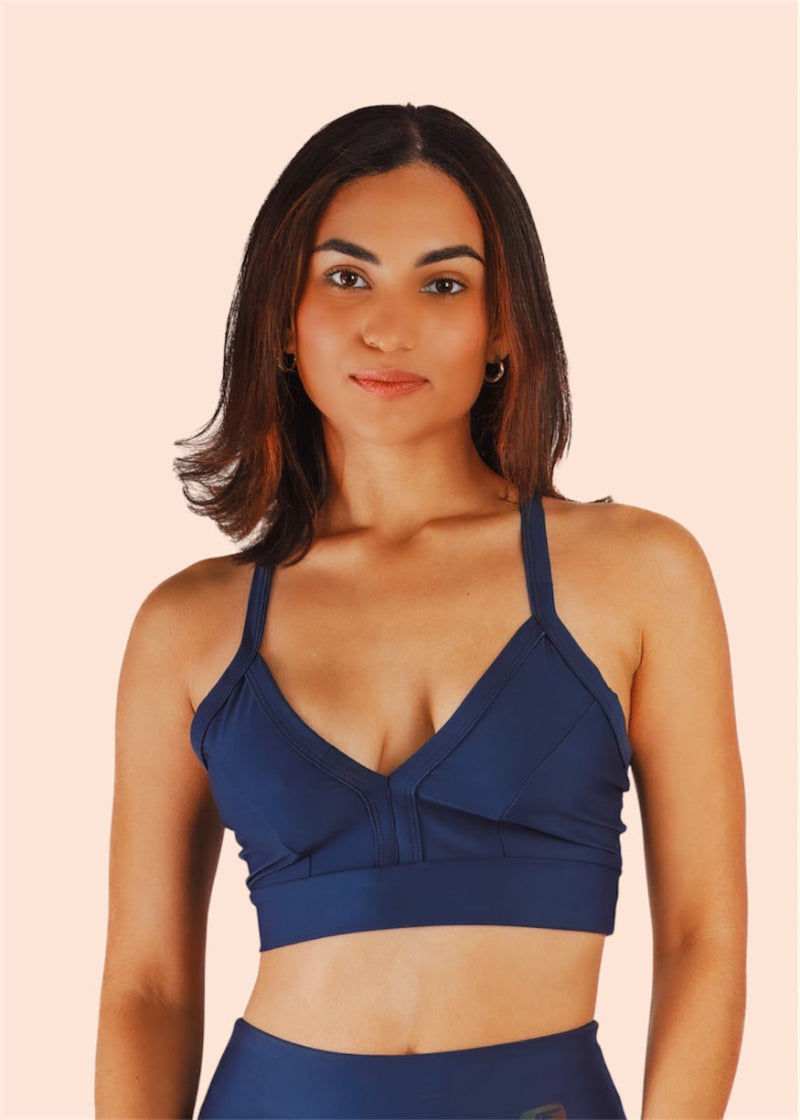 Woman wearing a blue sports bra and leggings on a beige background