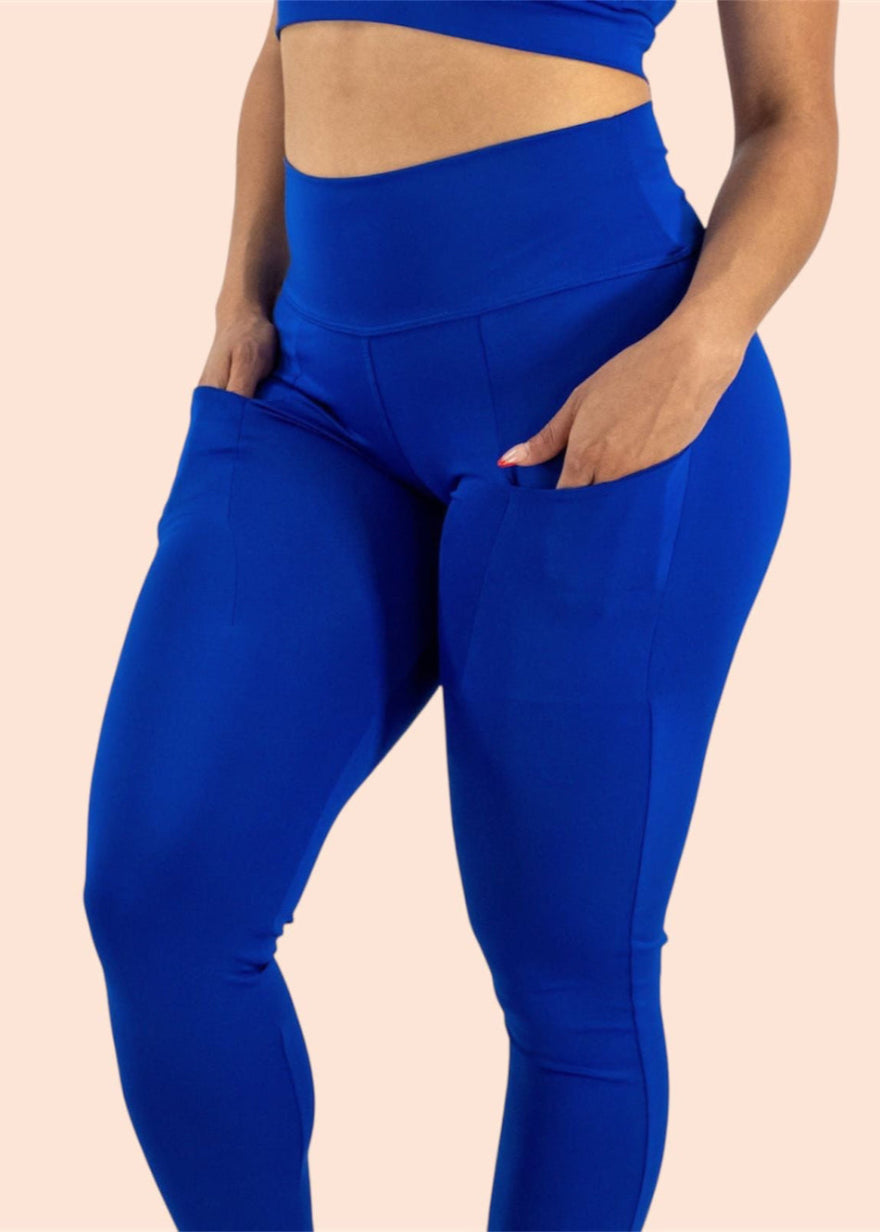 Person wearing blue athletic leggings on a beige background