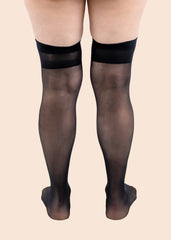 Black sheer tights worn by a person on a beige background
