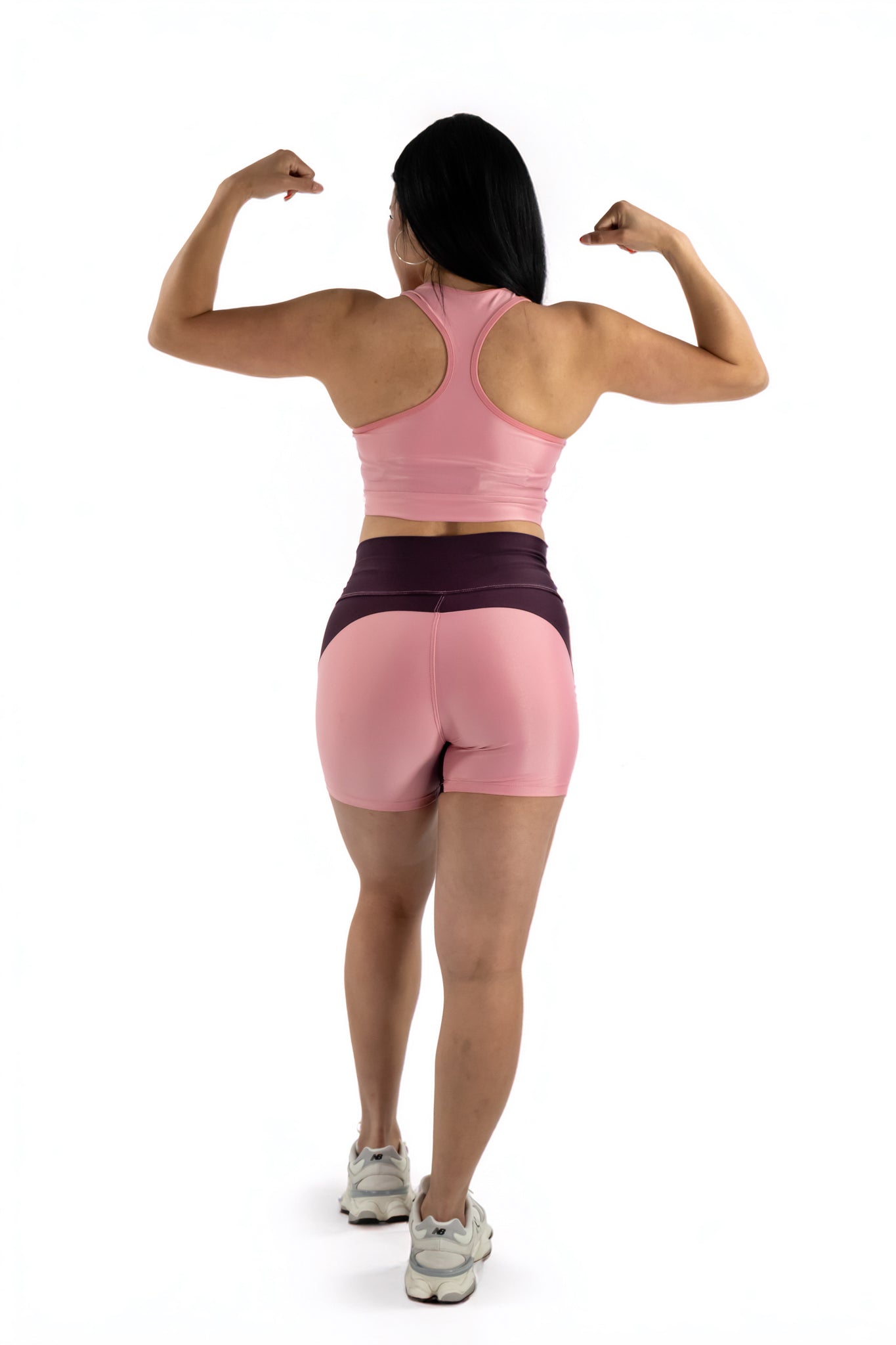 Person wearing a pink sports bra and shorts on a white background