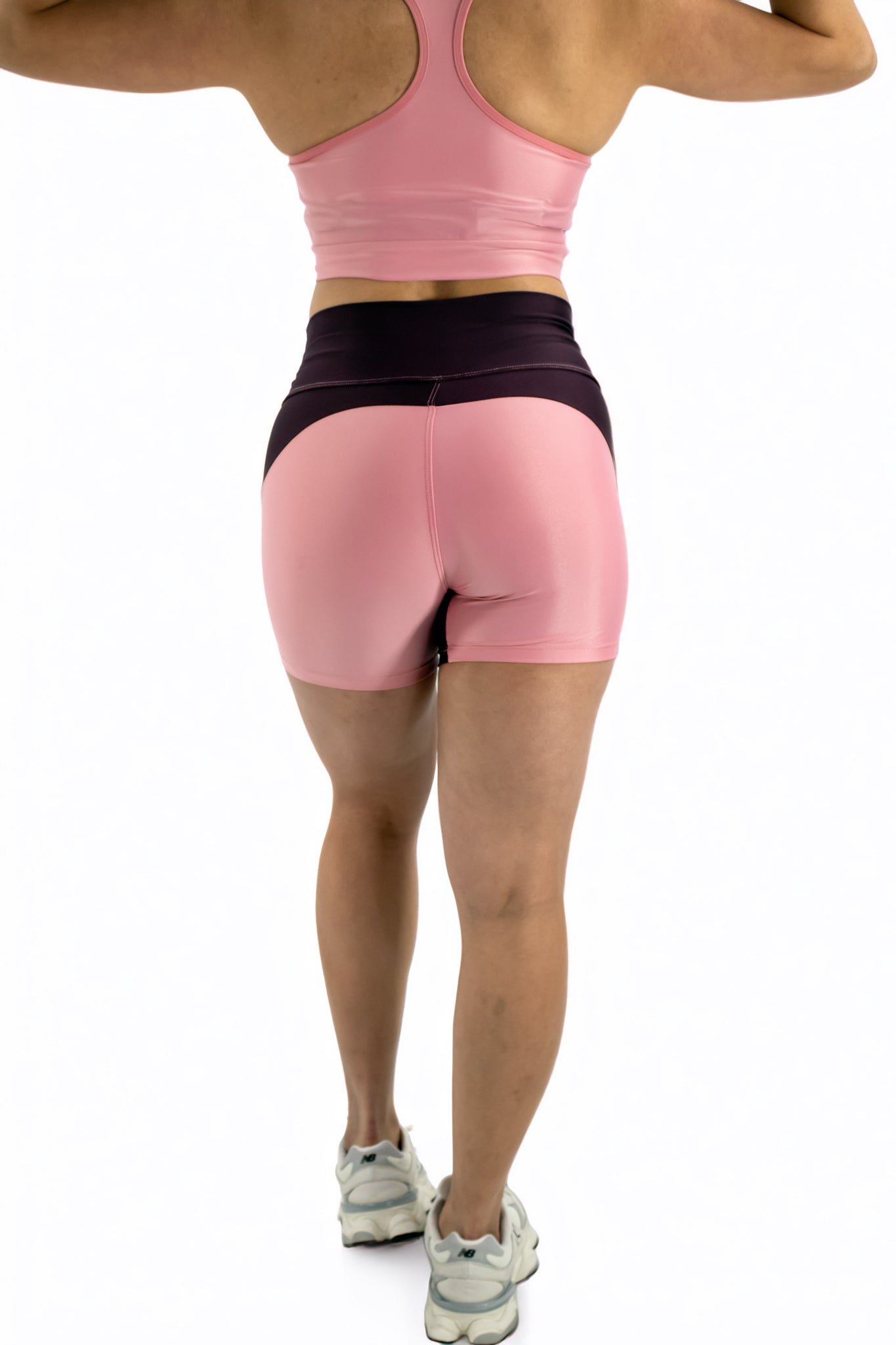 Person wearing pink athletic shorts and a sports bra on a white background