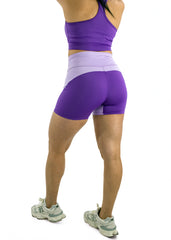 Person wearing purple athletic shorts and top on a white background