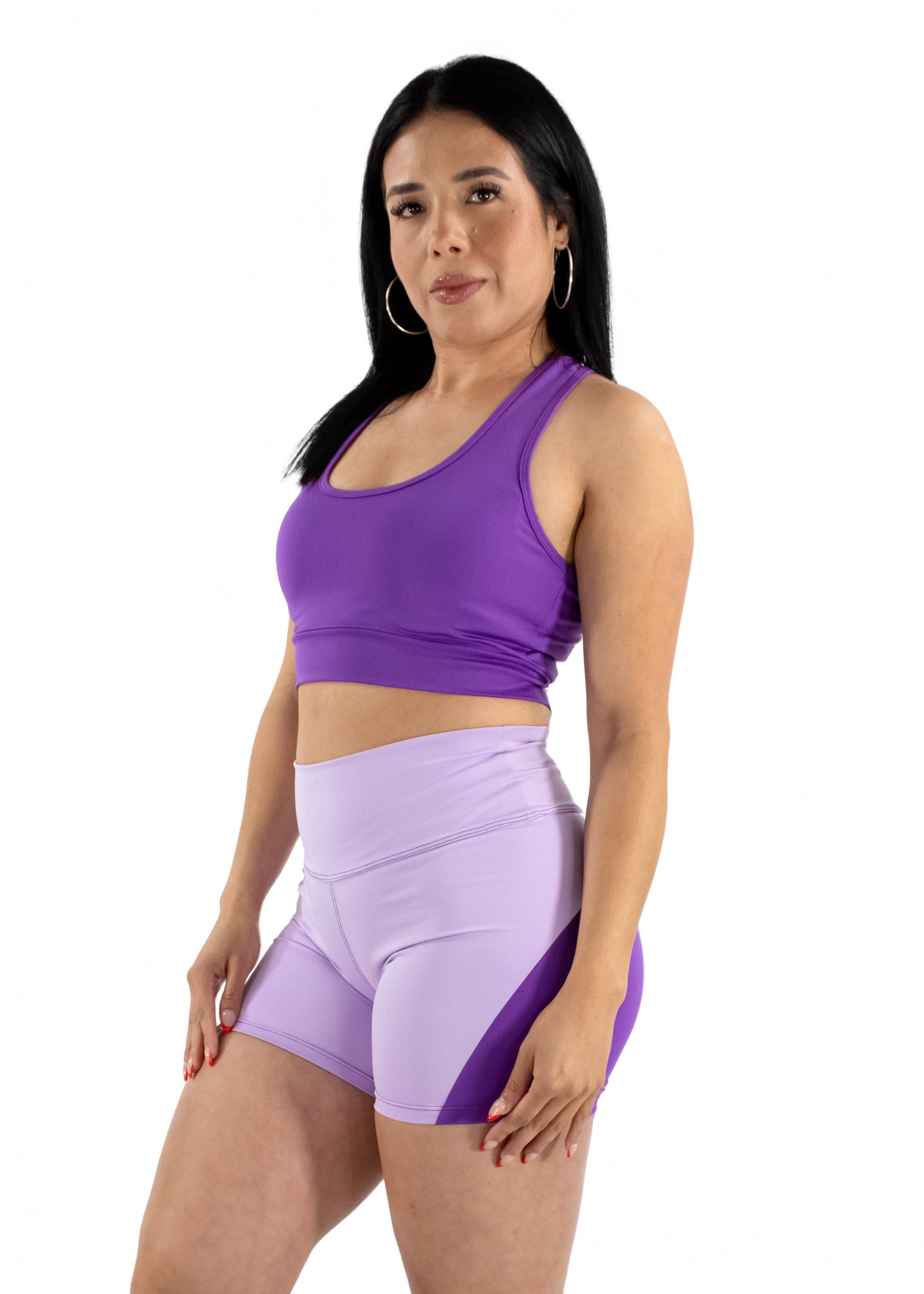 Woman wearing a purple sports bra and shorts on a white background