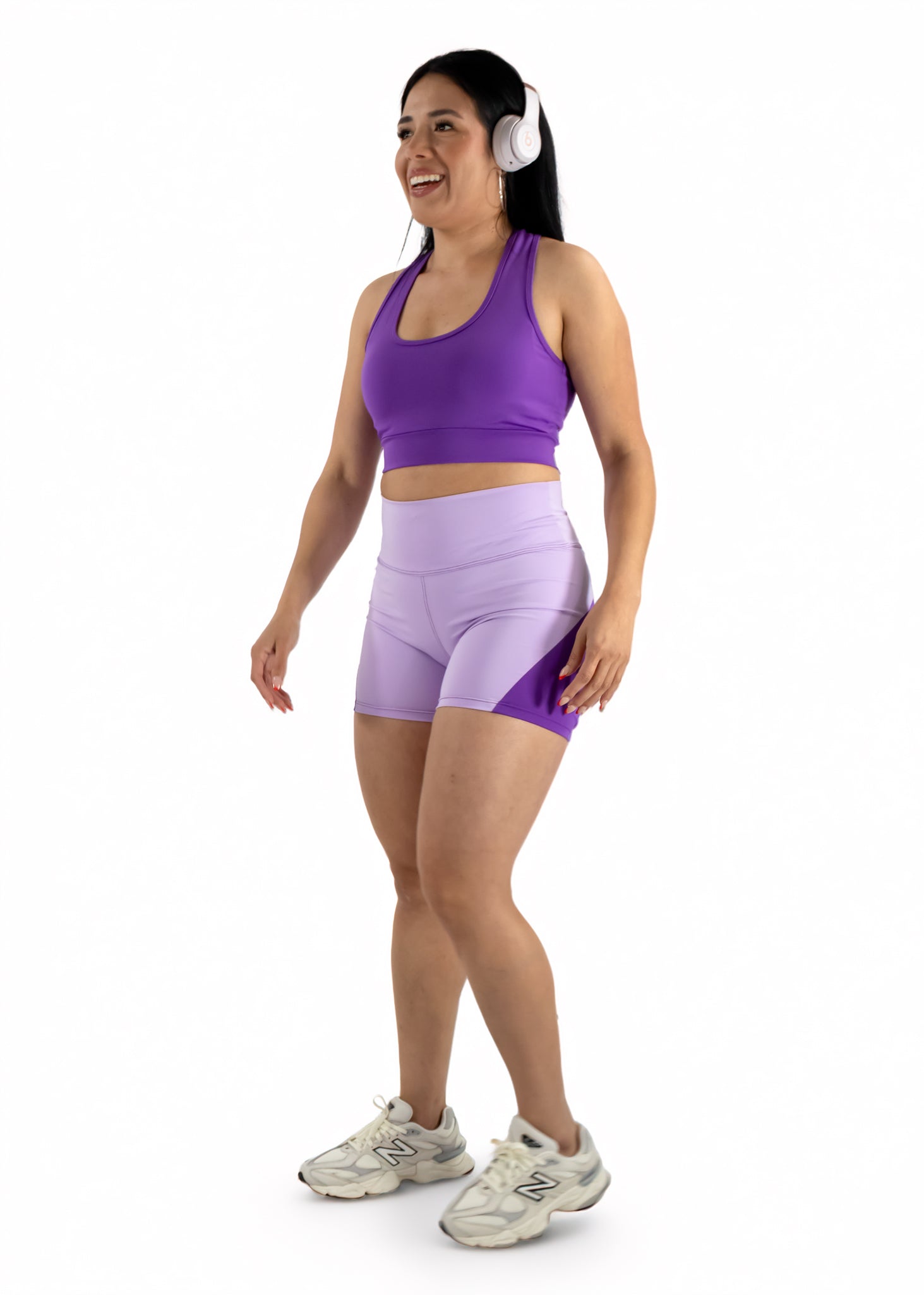 Woman wearing a purple athletic outfit with shorts on a white background