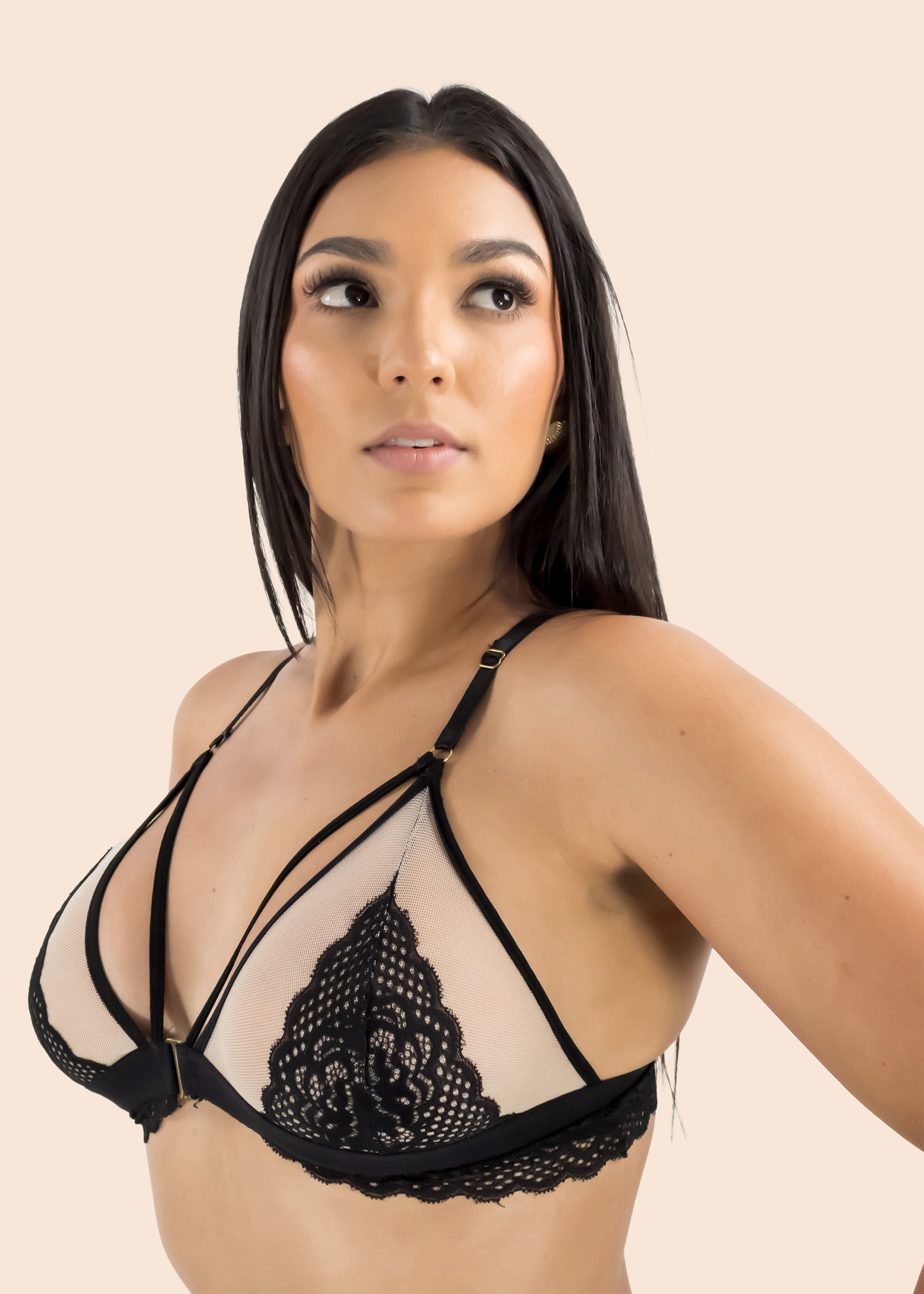 Woman wearing a black lace bralette against a beige background