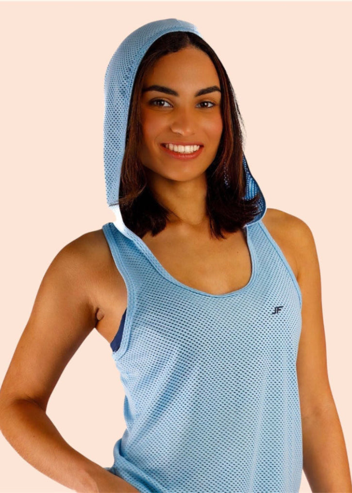 Woman wearing a blue athletic outfit with a hood on a beige background
