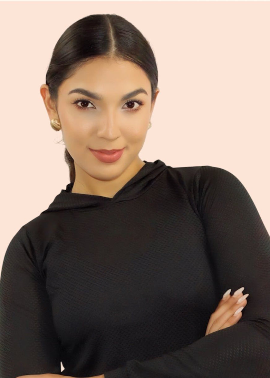 Woman wearing a black long-sleeve top against a light pink background