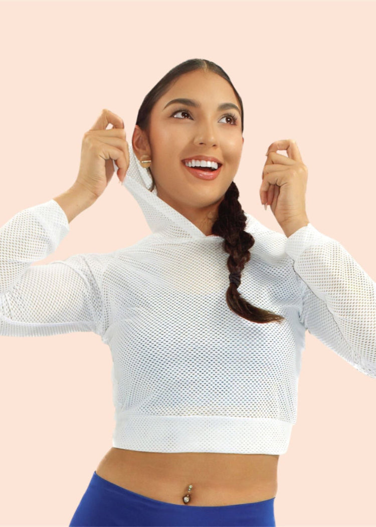 Woman wearing a white mesh long-sleeve top against a pink background