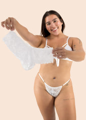 Woman wearing a white lace bra and panties set on a beige background