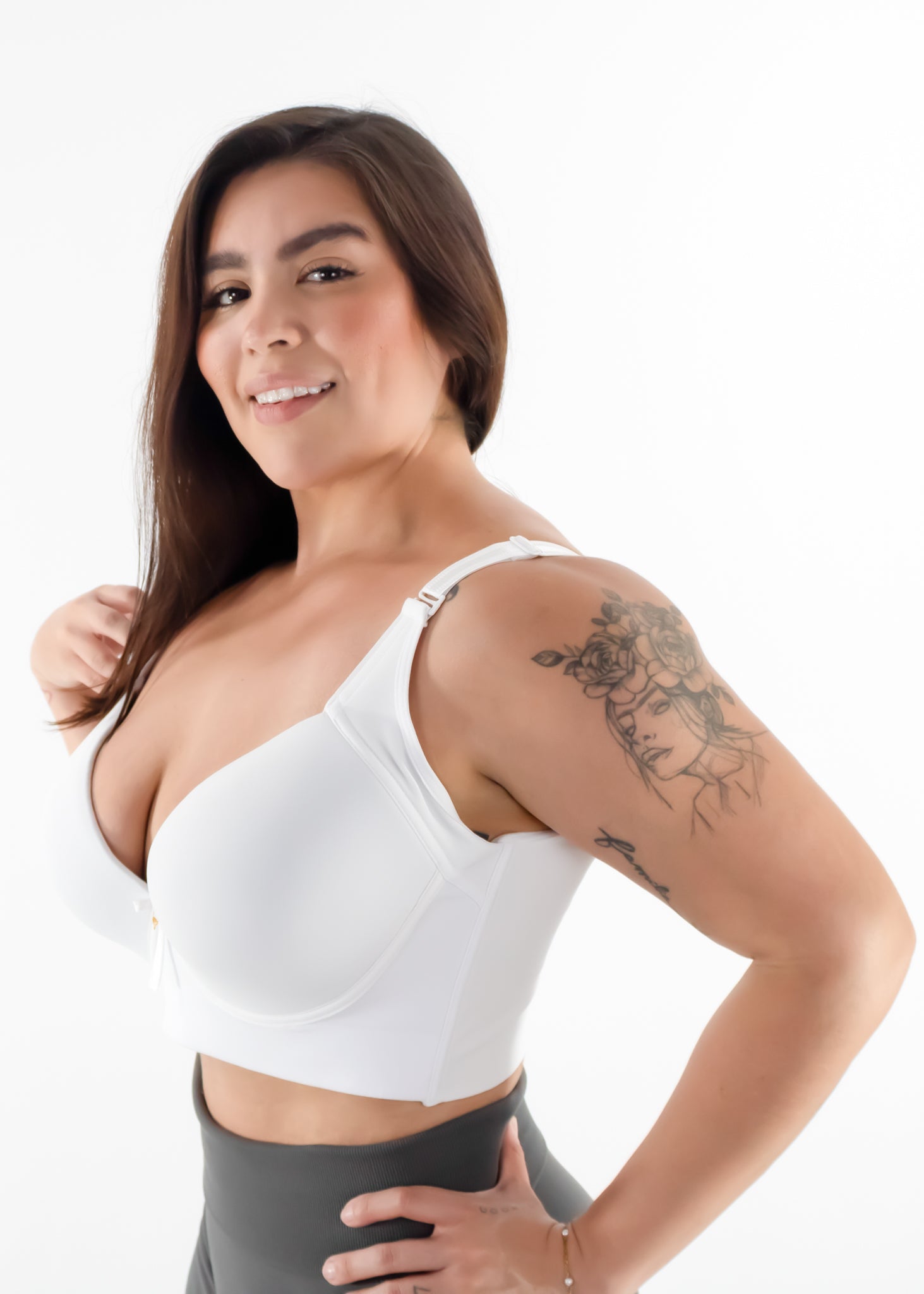 Woman wearing a white sports bra and gray leggings on a white background