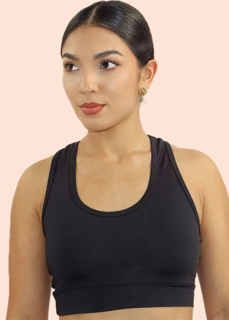 Woman wearing a black sports bra against a beige background