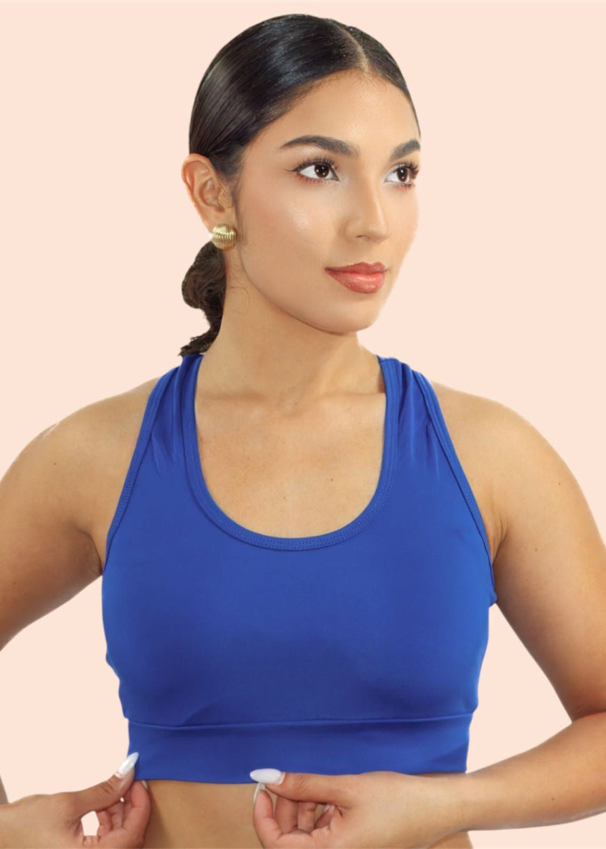 Woman wearing a blue sports bra against a beige background