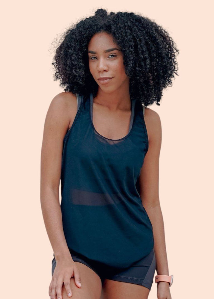 Woman wearing a dark green tank top and shorts on a beige background