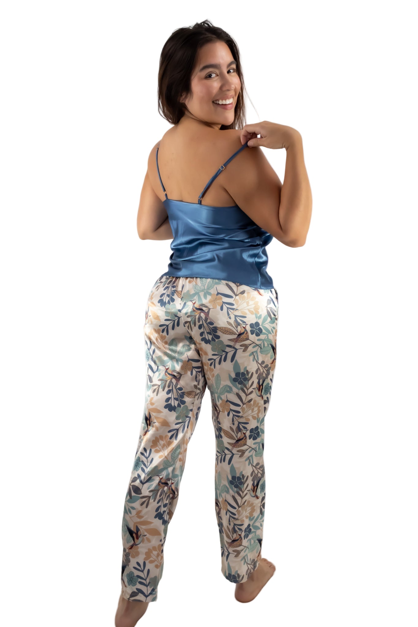 Woman wearing a blue satin top and floral pants on a white background