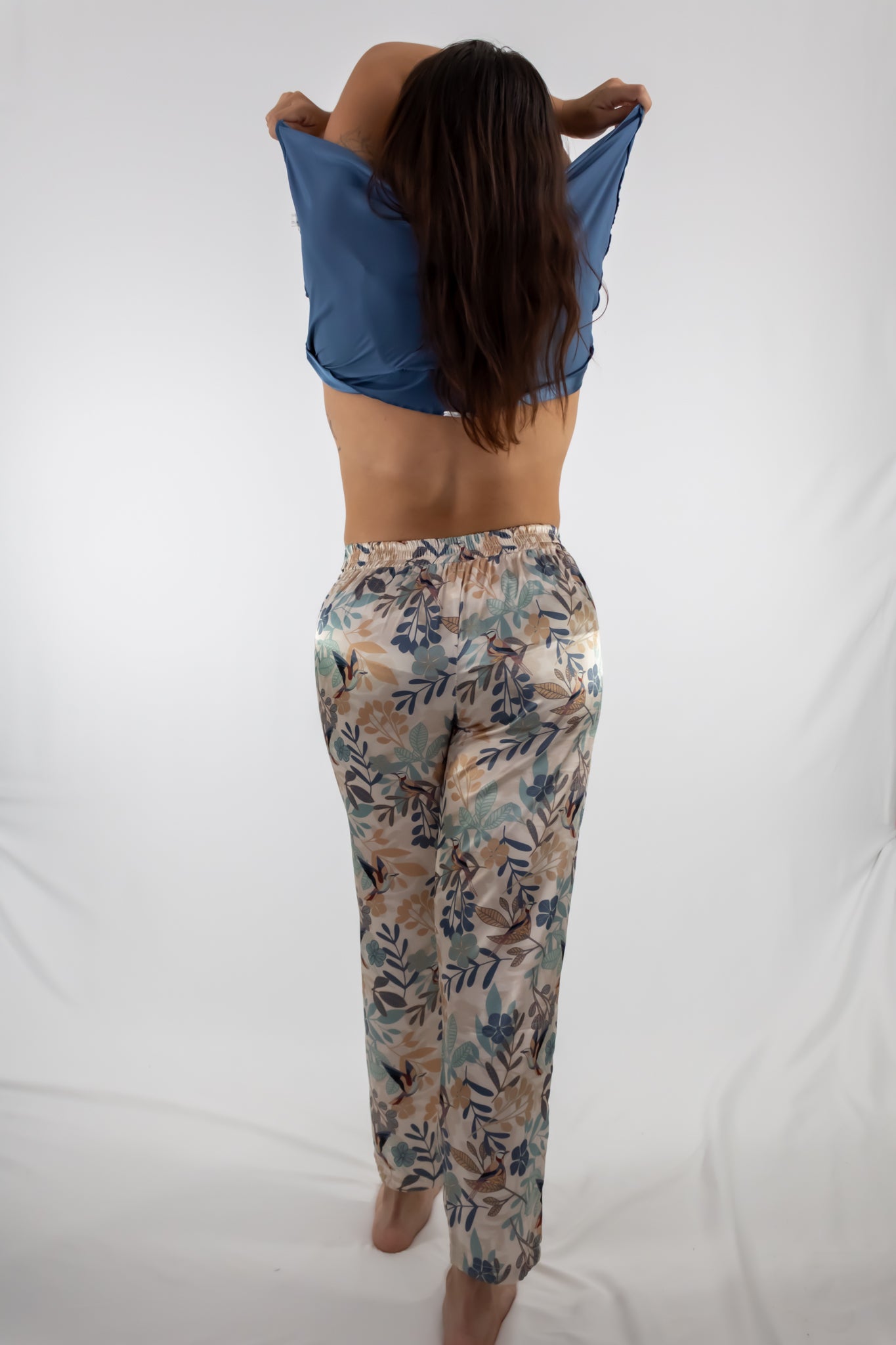 Person wearing a blue crop top and floral pants on a white background