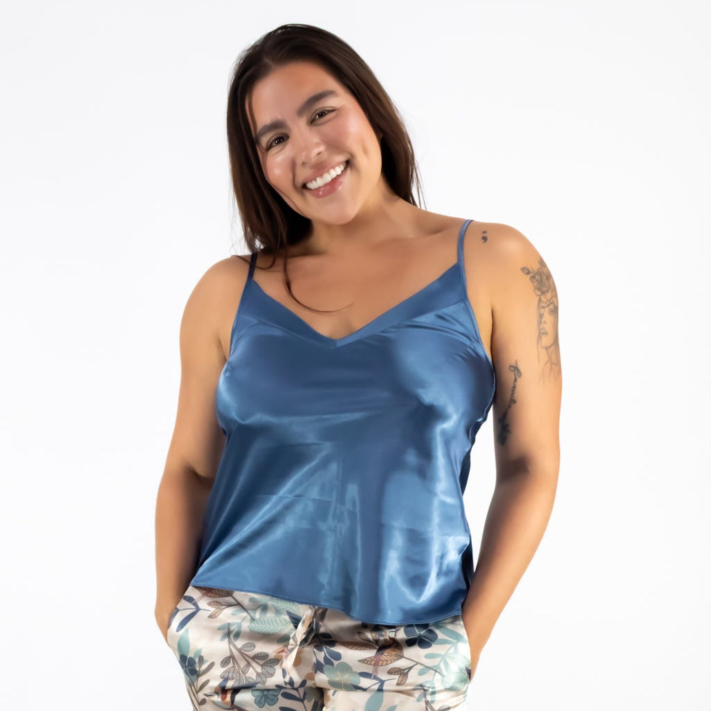 Woman wearing a blue satin top and floral pants on a white background