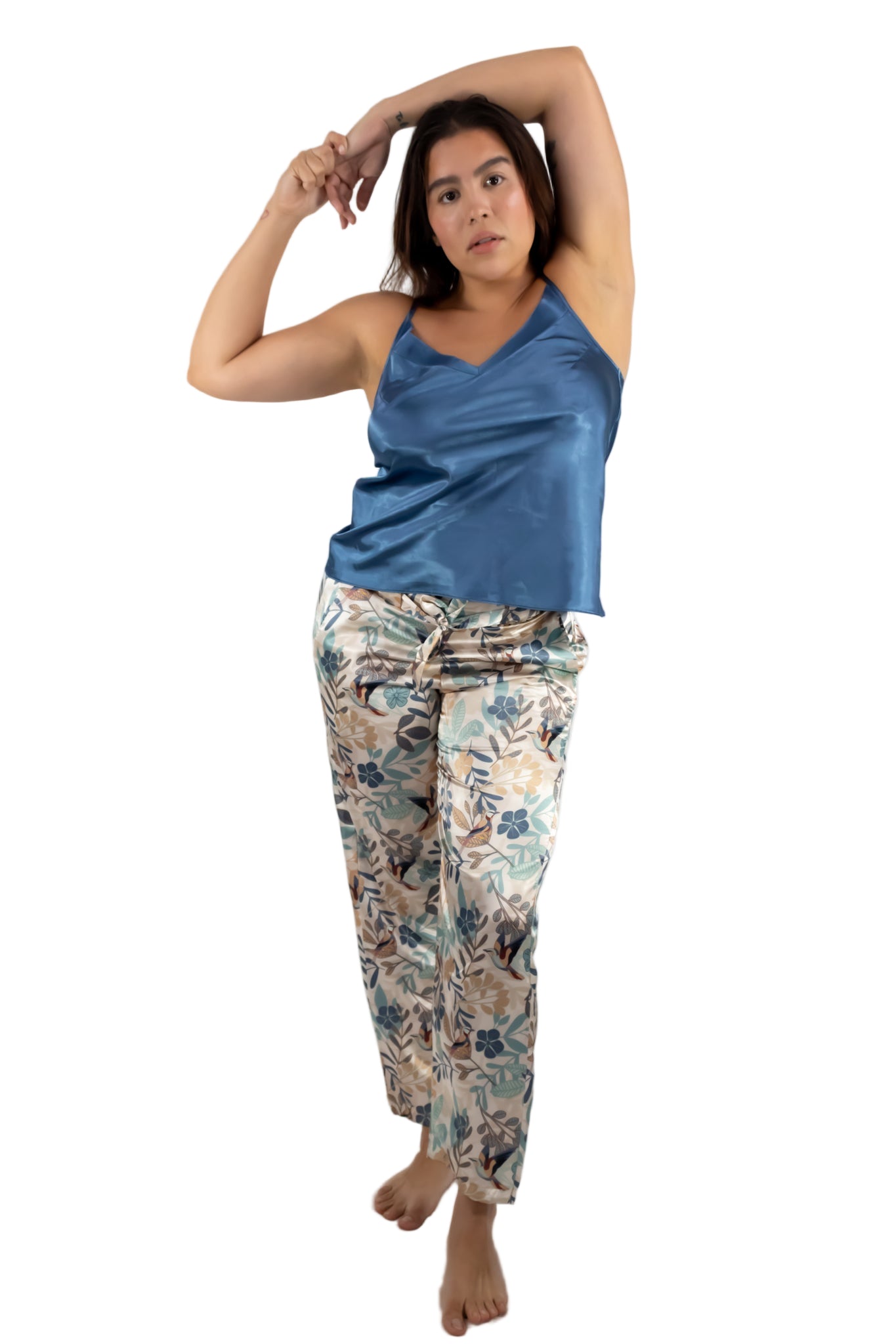 Woman wearing a blue satin top and floral pants on a white background