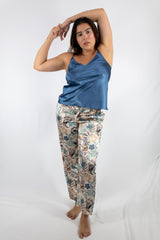 Woman wearing a blue satin top and floral pants on a white background