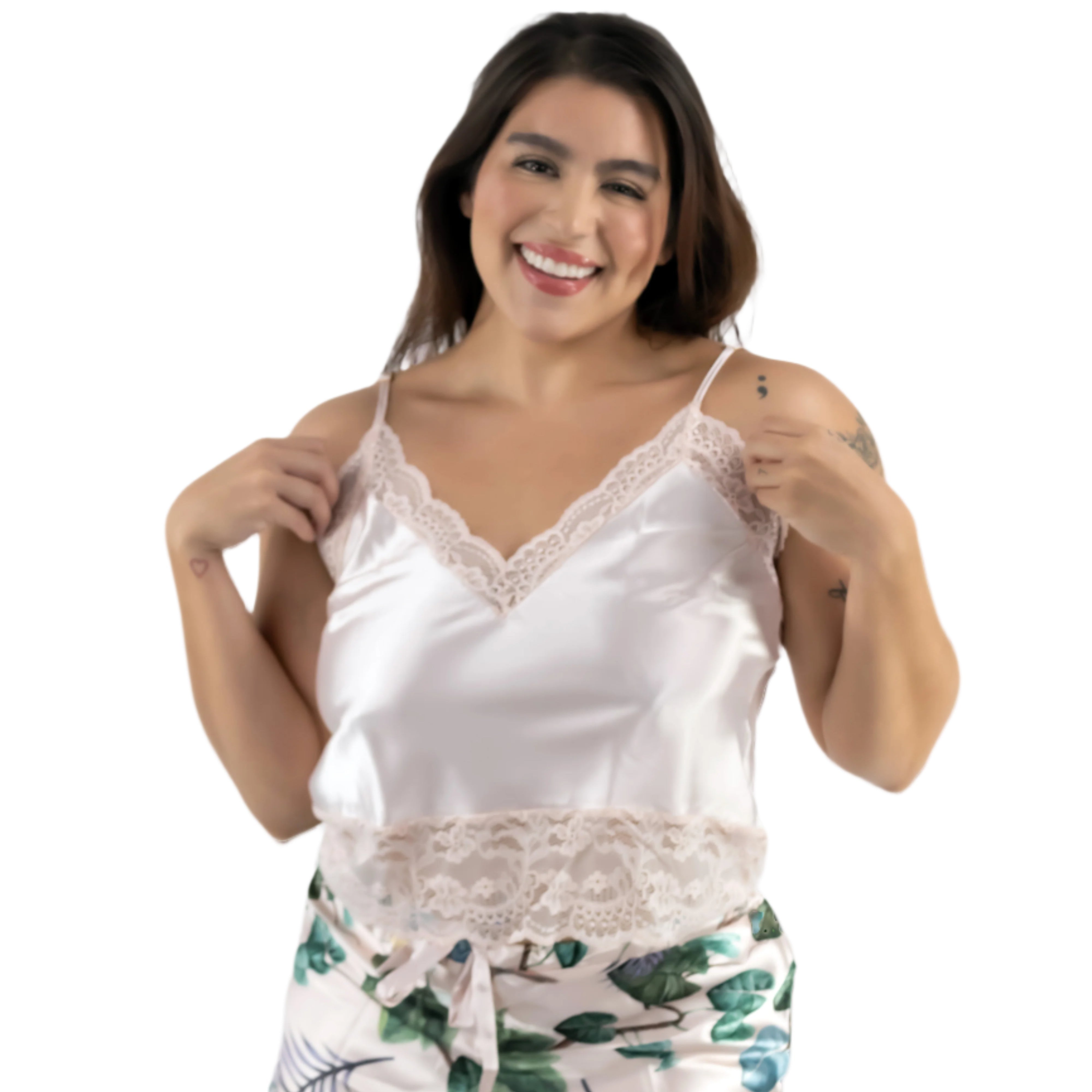 Woman wearing a beige satin camisole and floral shorts on a plain background