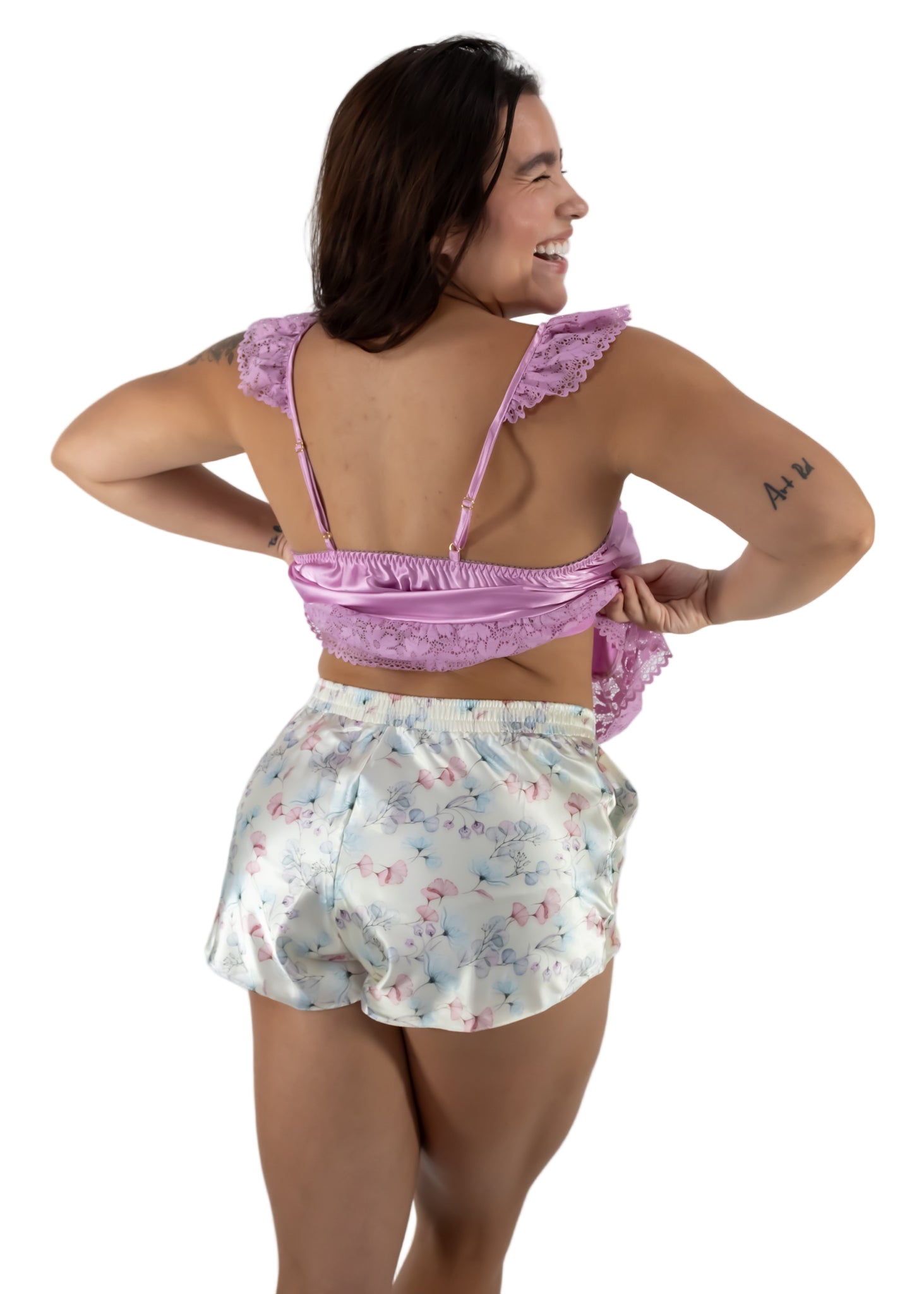 Woman wearing a pink top and floral shorts on a white background