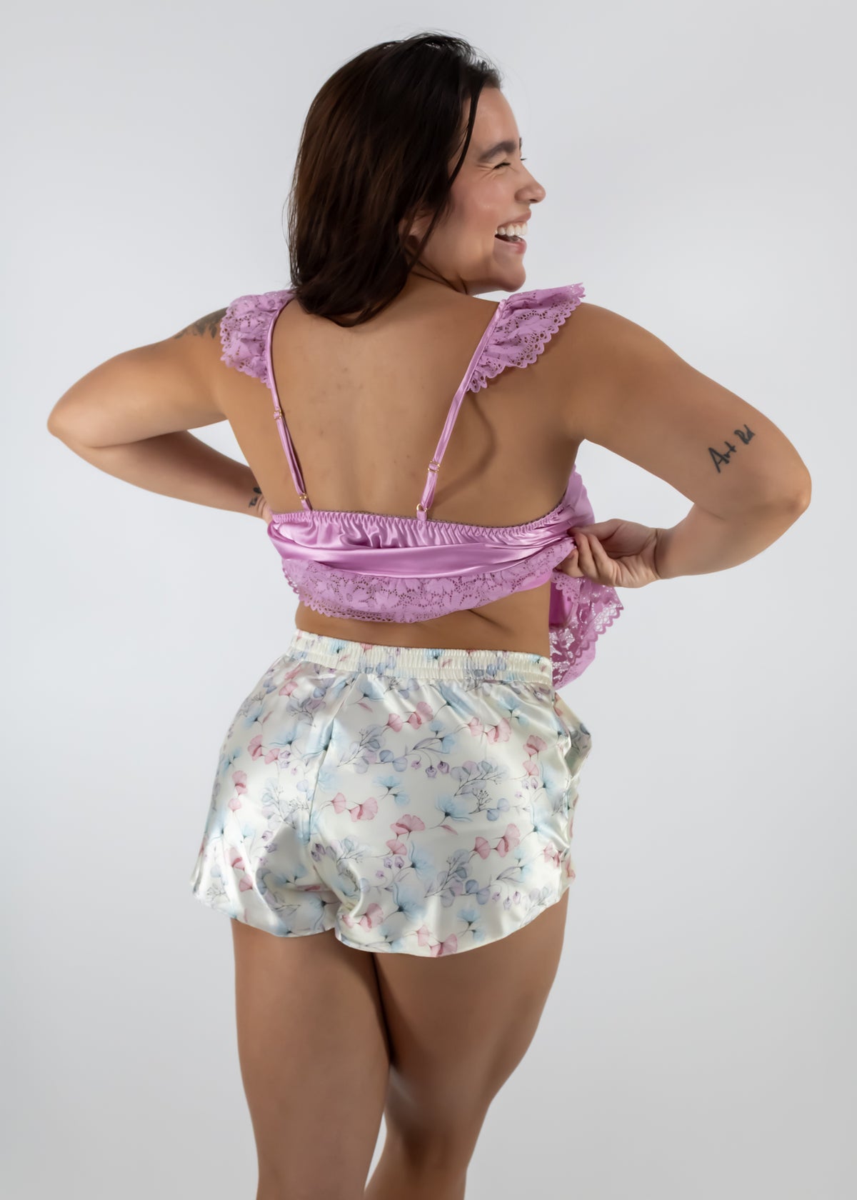Woman wearing a pink top and floral shorts on a white background