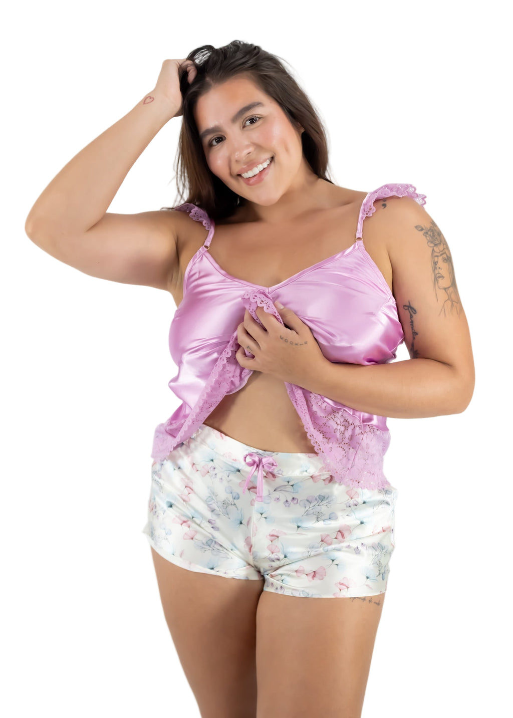 Woman wearing a pink satin top and floral shorts on a white background