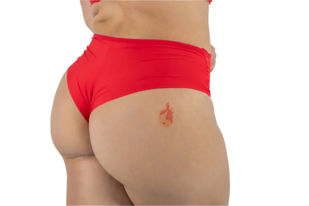 Person wearing red swim shorts with a small tattoo on the back of the leg.
