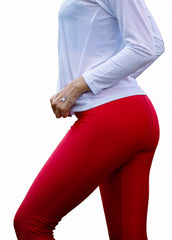 Person wearing a white long-sleeve top and red leggings on a white background