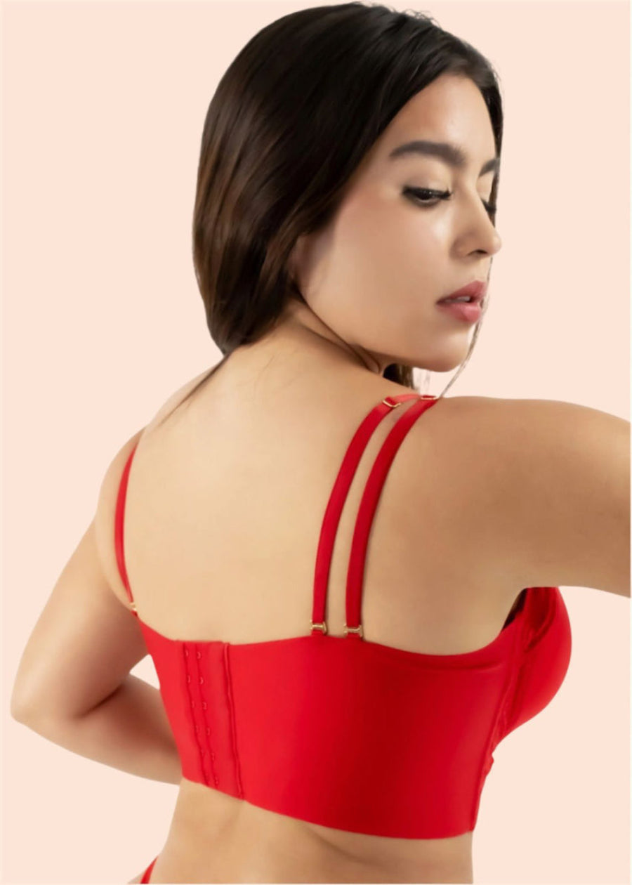 Woman wearing a red top with thin straps on a beige background