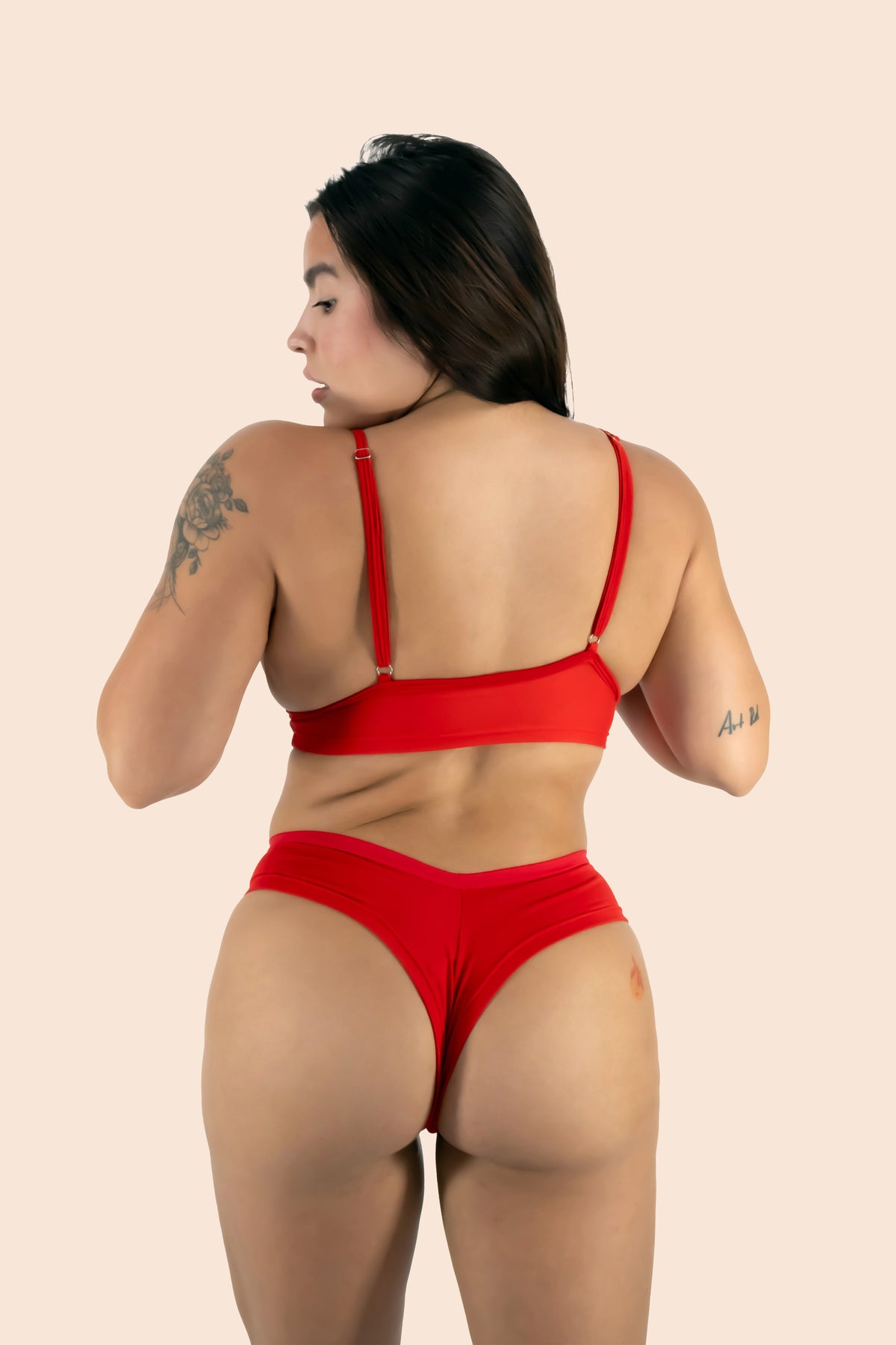 Person wearing a red bikini set on a beige background